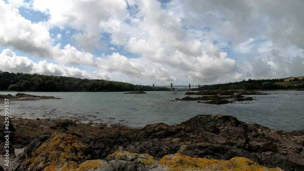 Rocky Welsh Menai Straits time lapse Britannia bridge transport crossing with clouds passing above Rocky Welsh Menai Straits time lapse Britannia bridge transport crossing with clouds passing above