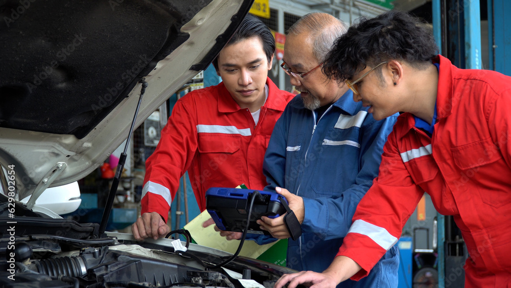senior asian car mechanic manager training apprentice to checking car engine by Diagnostics Software repair in garage . old asia Auto mechanic teaching trainee or assistant on the repair shop . senior asian car mechanic manager training apprentice to checking car engine by Diagnostics Software repair in garage . old asia Auto mechanic teaching trainee or assistant on the repair shop .