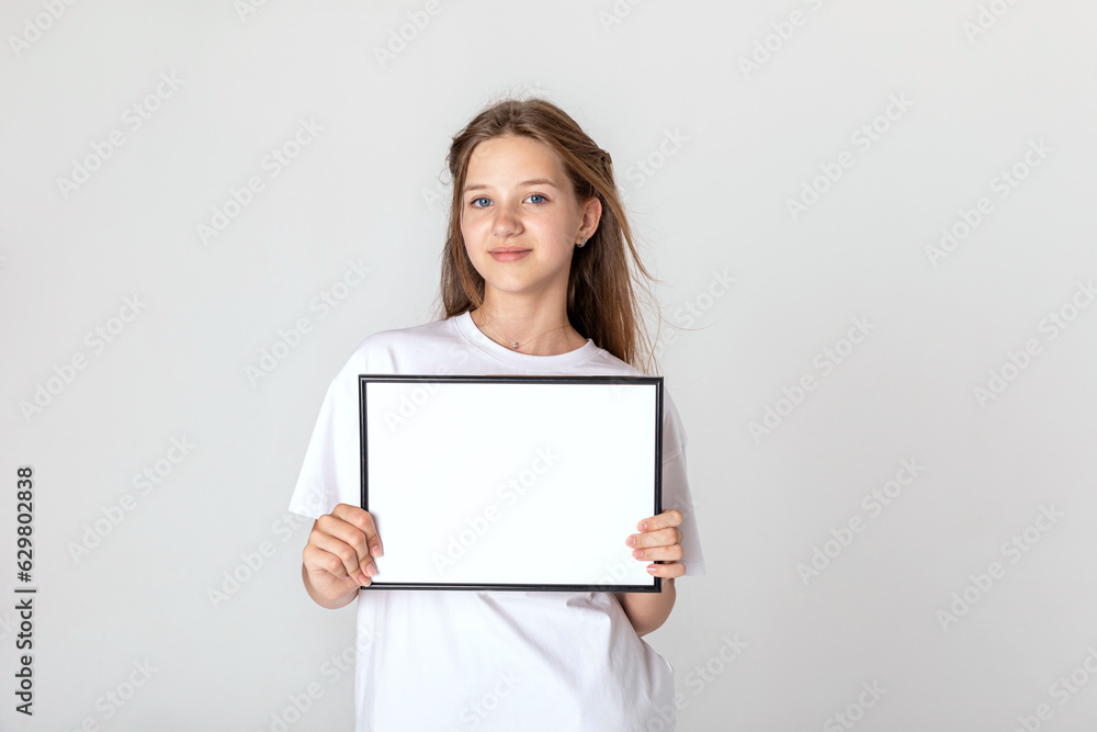 White banner .Teenager girl hold white blank paper. Young smiling woman show blank board. Close up female model portrait on white background. White banner .Teenager girl hold white blank paper. Young smiling woman show blank board. Close up female model portrait on white background.