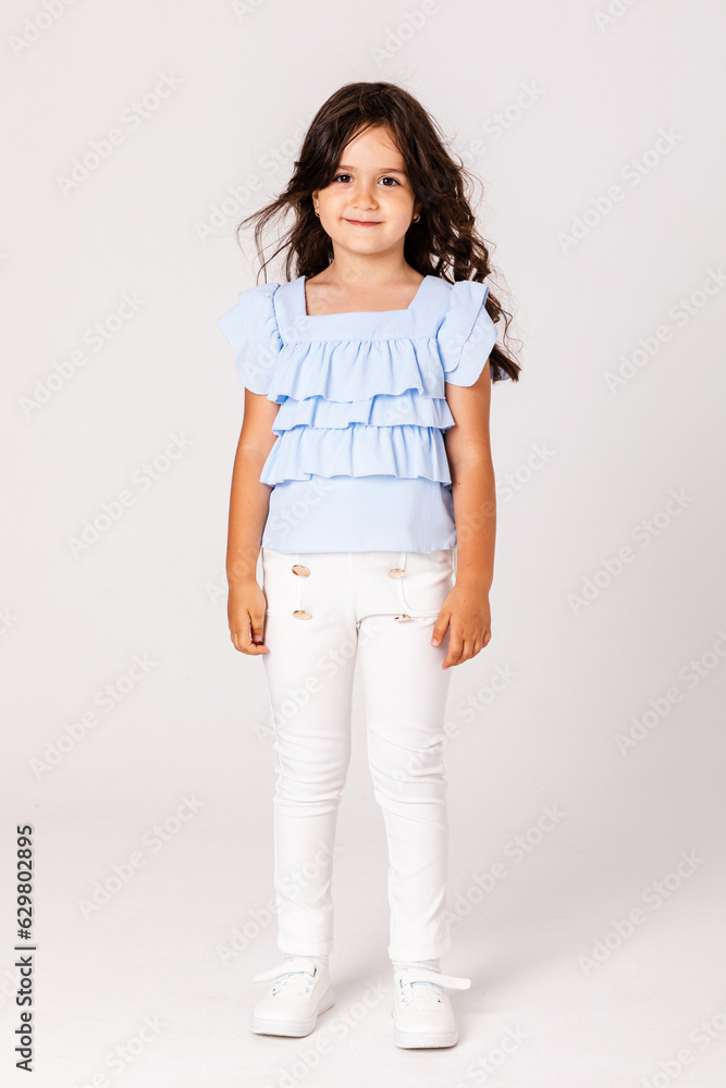 High fashion look.glamor stylish beautiful happy surprised little girl model in summer blue and white cloth on white background. High fashion look.glamor stylish beautiful happy surprised little girl model in summer blue and white cloth on white background.