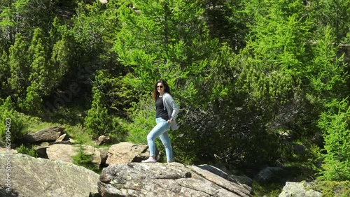 Woman standing on rock and hikers or trekkers walking surrounded by nature of Val Masino in Valtellina, Italy. Real time photo