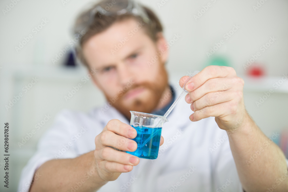 male researcher holding pipette with liquid male researcher holding pipette with liquid