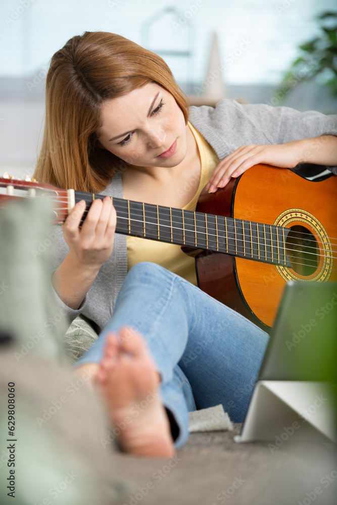 Fototapeta premium young woman playing a guitar at home