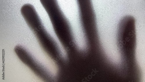 Male hand silhouette shadow behind translucent mirror sliding slowly