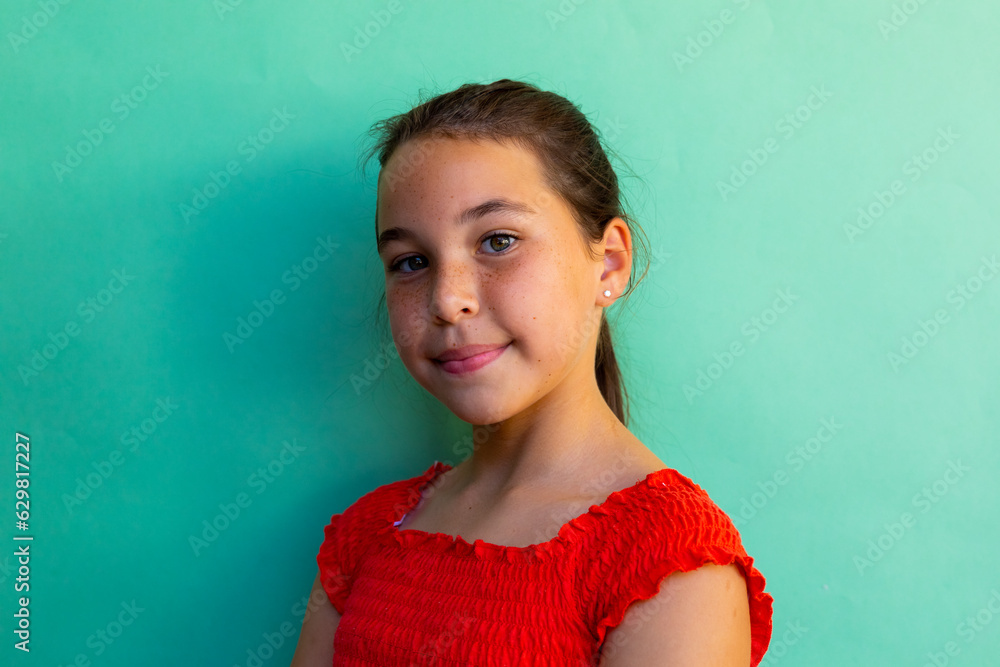 Obraz premium Portrait of happy caucasian schoolgirl wearing dress over blue background