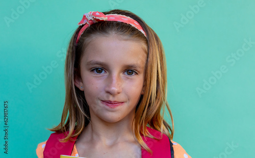 Portrait of happy caucasian schoolgirl with band over blue background at elementary school