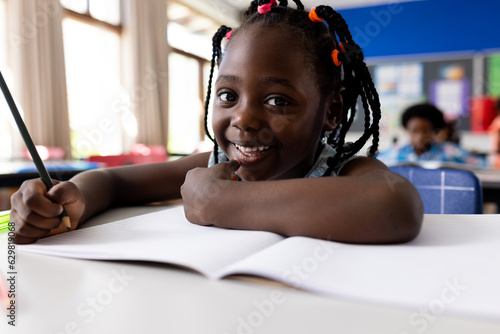 Portrait of african american girl writing in classroom at elementary school photo