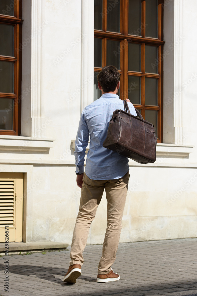 Handsome businessman walking on the street, with luxury brown leather briefcase. Fashionable style.