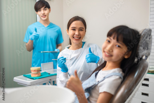 Children's dentistry for healthy teeth .Close-up happy little child asian girl smiles looking at camera, sitting in dentist's chair, receiving dental.