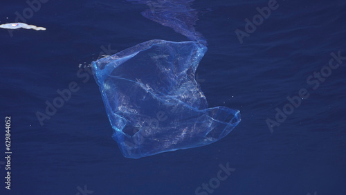 Disposable blue plastic bag floats under surface in blue water. Plastic bag thrown into sea drifts under surface of blue water in morning time, Red sea, Egyp