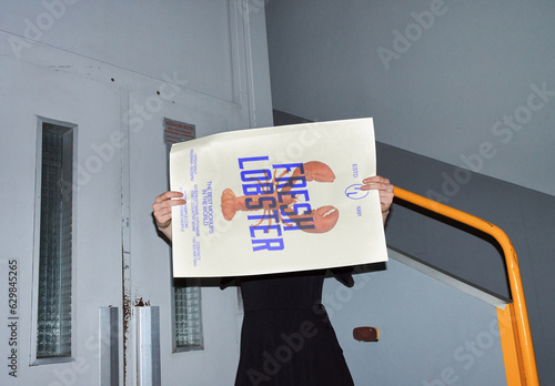 Mockup of woman holding customizable A2 poster in front of face, camera flash