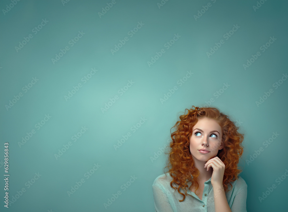 Portrait of a young woman in green shirt looking up thinking, isolated on green studio background