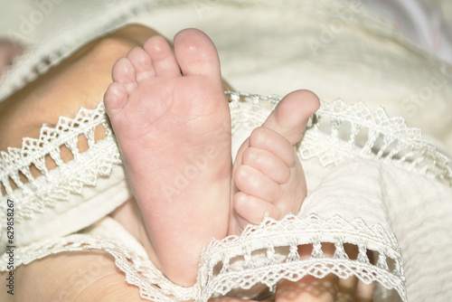 The legs of a newborn baby in a white cloth. Wrapped baby's little feet
