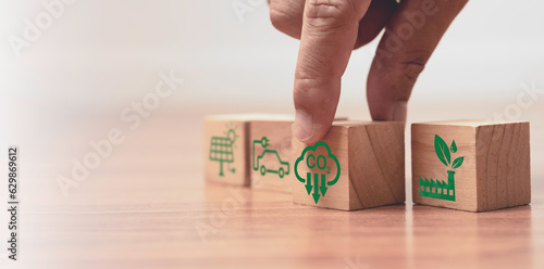 Hand pushing carbon reduction on wooden block cube for for decrease CO2 , carbon footprint and carbon credit to limit global warming from climate change, Bio Circular Green Economy concept.