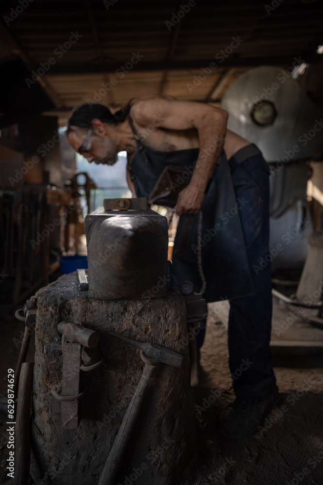 custom made wallpaper toronto digitalSelective focus on an anvil with a blacksmith in the background in a forge shop.