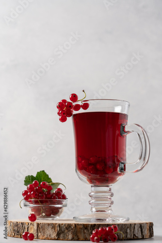 Red currant hot tea in a transparent mug on a light background. Berry vitamin cocktail close-up view