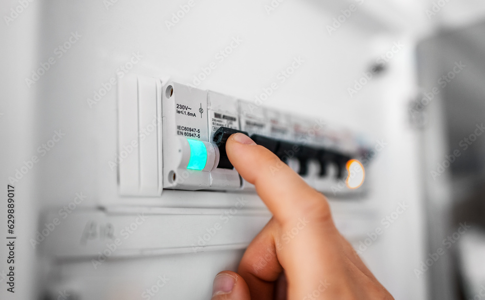 Male hand switching on fuse board.