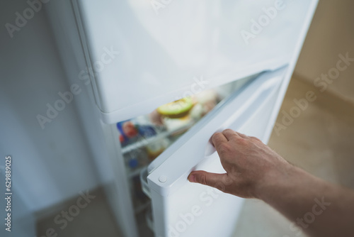 Man opening door of refrigerator with food.
