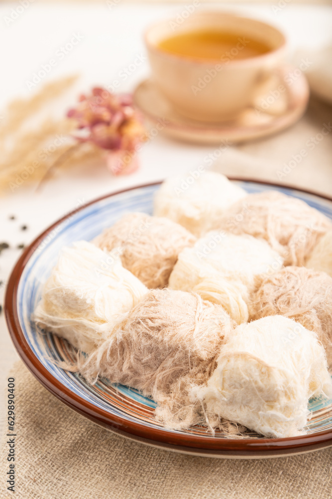 traditional arabic sweets pishmanie and a cup of green tea on white wooden,  side view, selective focus.