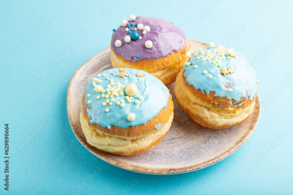 Purple and blue glazed donut on blue pastel, side view.