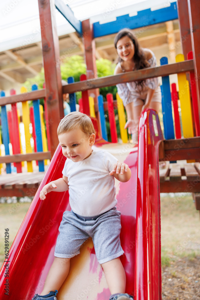 Mother and child playing on a slide in the park Mother and child playing on a slide in the park