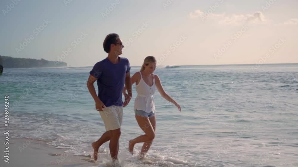 Couple running on empty beach in Thailand holding hands Couple running on empty beach in Thailand holding hands