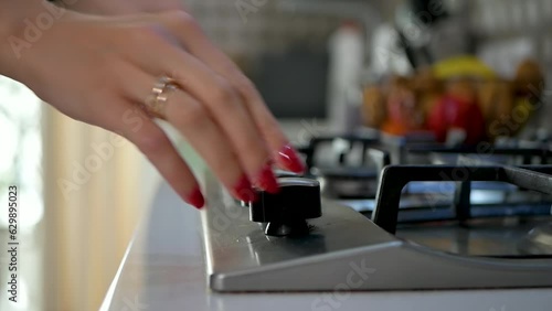 close-up of a woman's hand with a beautiful manicure lighting a gas stove for cooking the home comforts of the modern world igniting the gas using a permanent igniter