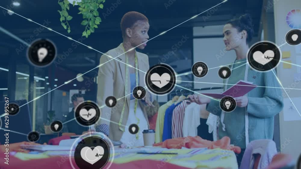 Animation of connected heartbeat and lightbulb icons, diverse fashion coworkers discussing in studio Animation of connected heartbeat and lightbulb icons, diverse fashion coworkers discussing in studio