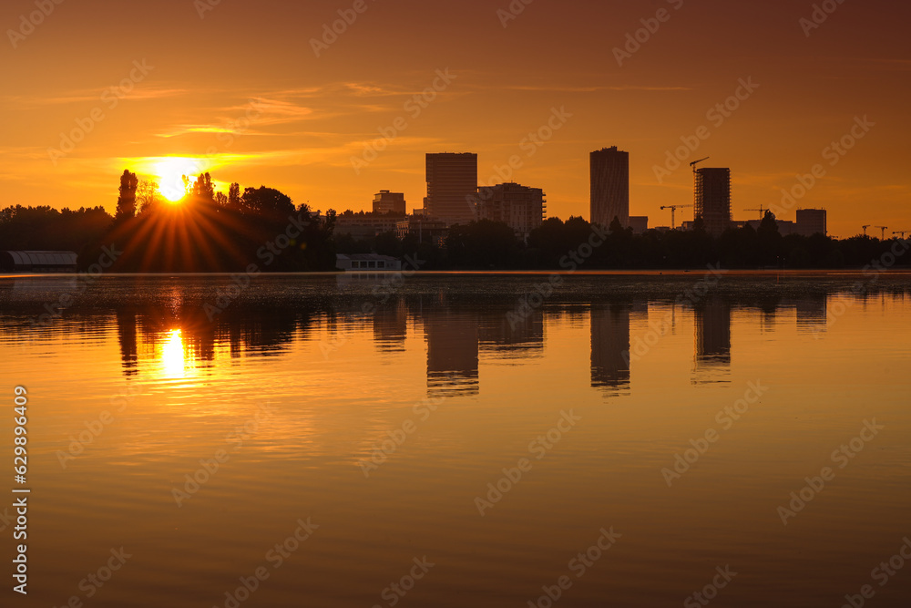 Obraz na płótnie Bucharest at sunrise. beautiful morning orange sky landscape of the city skyline and its reflection in Herastrau Lake. Travel to Romania. w salonie