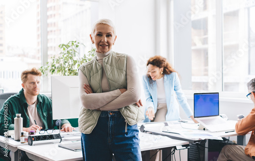 Positive mature woman with arms folded in light office