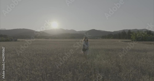Chica andando por atardecer por el campo de trigo ( log footage )