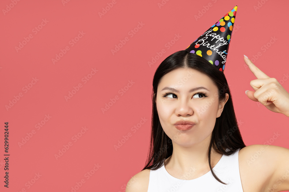 Asian girl with a holiday cap on her head, pointing with her finger Asian girl with a holiday cap on her head, pointing with her finger