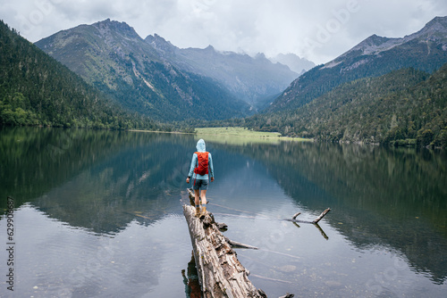 Hiking woman walking on a one plank bridge in high altitude mountains