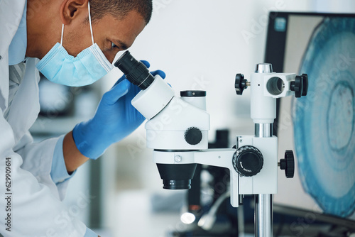 Microscope, science and man with mask on face in laboratory to review particles, medical test and biotechnology. Scientist, microbiology and investigation of innovation, dna analysis and development