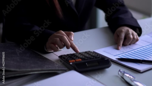 Young Asian businesswoman using a calculator to for doing  finance report working at office desk.