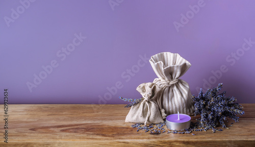 Dry lavender, bouquet of lavanda flowers, organic aromatic herbs in linen sachets and aroma candle on wooden table, aromatherapy collection in Provence style. Sack of fragrant lavand for spa flyer.