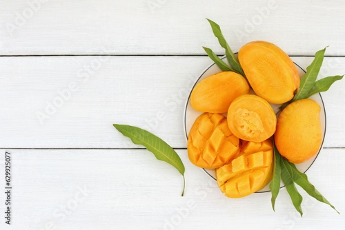 Fresh and beautiful mango fruit with sliced diced mango chunks on a light wooden background, copy space(text space), blank for text, topview.