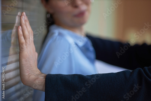 Closeup of man pushing woman against wall in office, workplace harassment scene photo