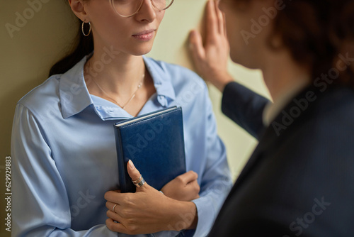 Closeup of male boss intimidating young woman in office pushing her against wall, copy space