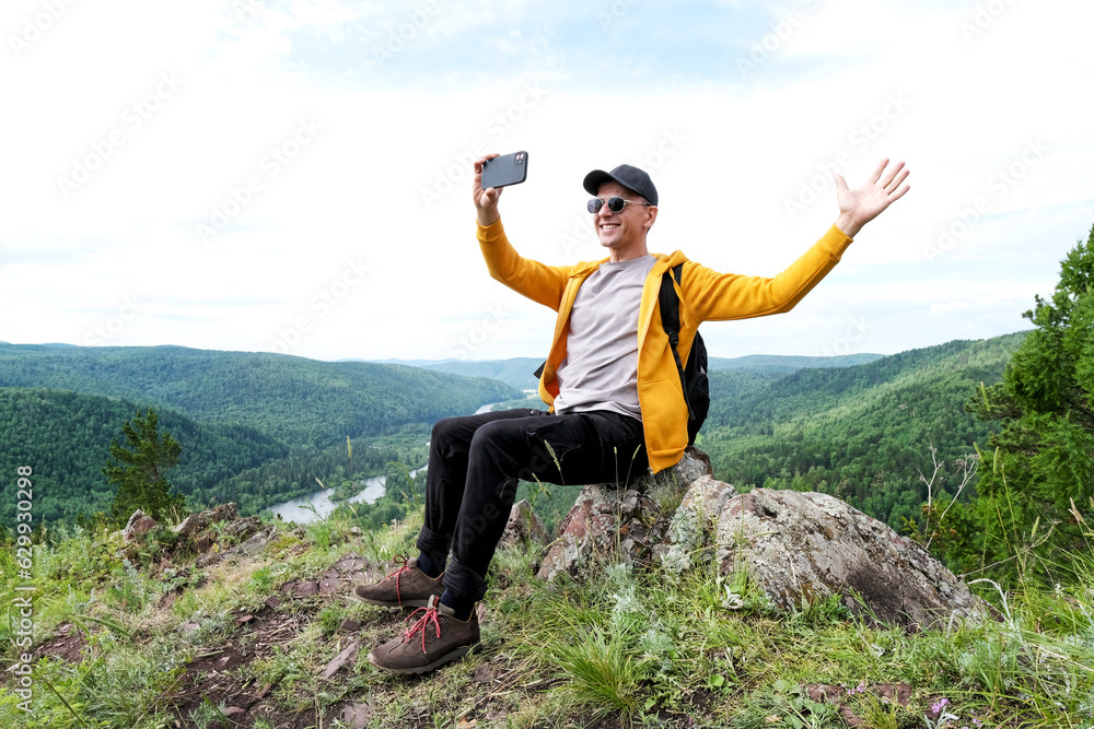 man with backpack have a rest during hiking mountains. Tourist drink water and relax, sitting rock at the top of hill. man with backpack have a rest during hiking mountains. Tourist drink water and relax, sitting rock at the top of hill.