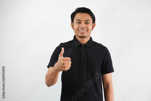 portrait of smiling young Asian man give thumb up wearing black polo t shirt isolated on white background
