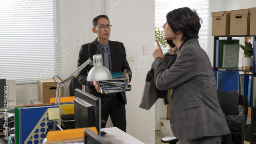 Foto asian male employee packing bag is pretending to answer a phone call and leaving the office in a rush while his boss tries to give him more paperwork