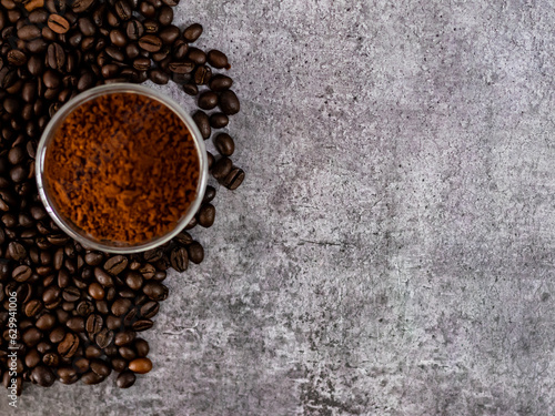 Top shot of roasted coffee beans with defocused coffee powder and copy space.