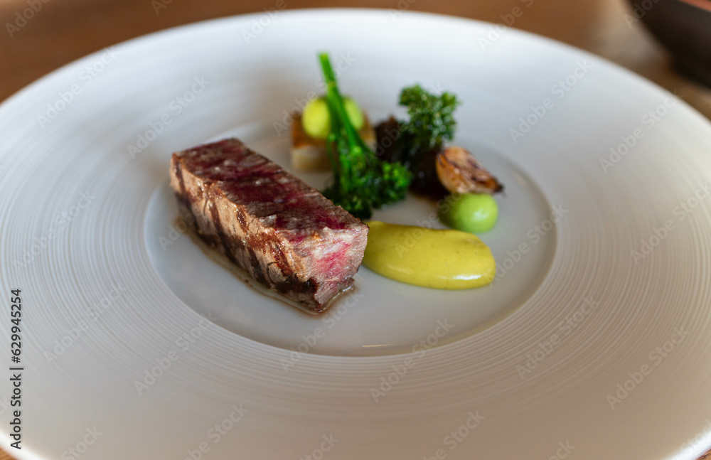 Wagyu cut with broccoli and mustard on a white plate in gastronomic restaurant