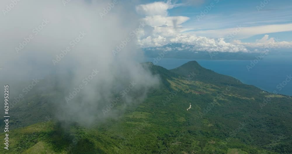 Tropical mountain with green trees, jungle, and forest. Blue sky and clouds. Camiguin Island. Philippines.