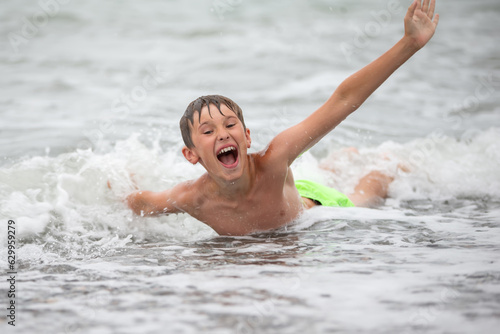 Happy boy playing with the sea wave, enjoying the sea. The child bathes, sunbathes and rests. Summer holidays.