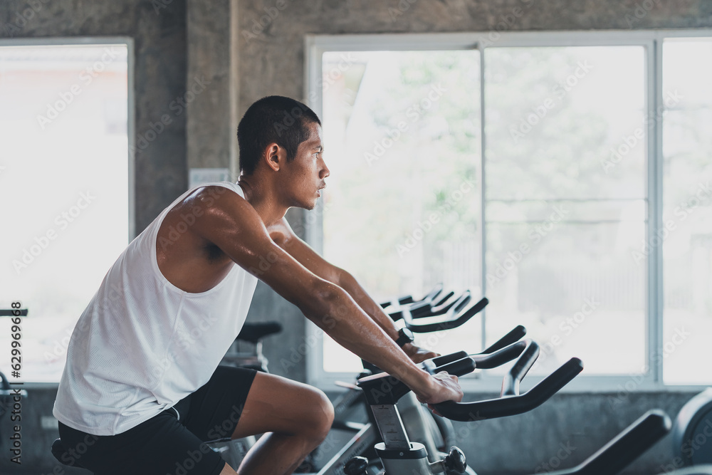 Φωτογραφία Asian sportsman exercising on a bicycle in the gym, determination to cardio lose weight, makes her healthy