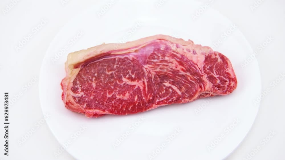 New york strip steak boneless meat cut macro closeup on plate isolated on white background with zooming zoom in shot New york strip steak boneless meat cut macro closeup on plate isolated on white background with zooming zoom in shot