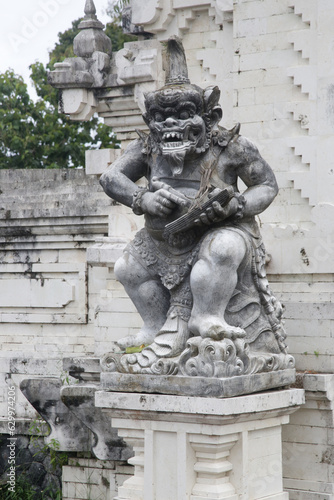 Balinese white sandstone statue in front of temple