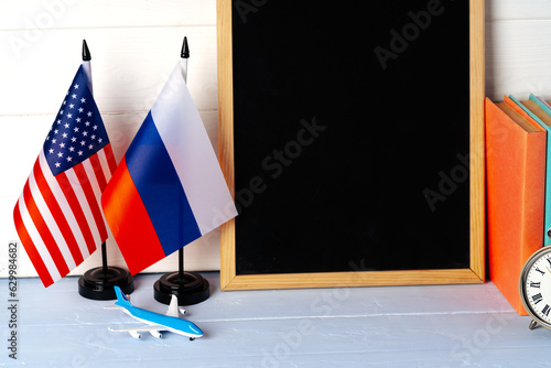 Blank blackboard with USA and Russia flags on wooden background photo